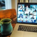 Remote team on a video call with a laptop and coffee on the desk