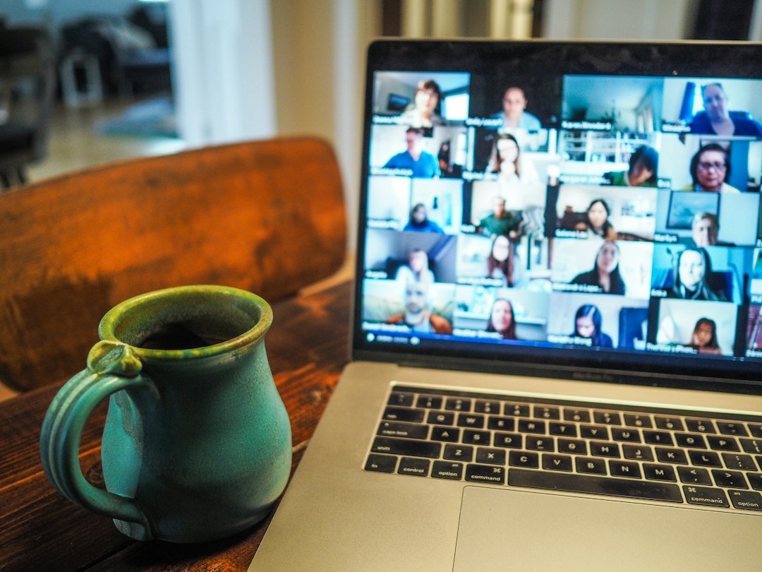 Remote team on a video call with a laptop and coffee on the desk