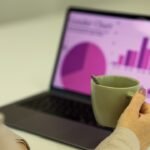 Small business owner working at a laptop while reviewing a chart, illustrating business workflow automation